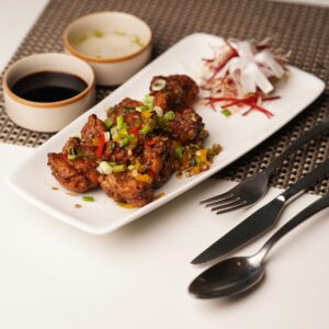 Savor the taste of Asian-style fried meat garnished with fresh vegetables and soy sauce.