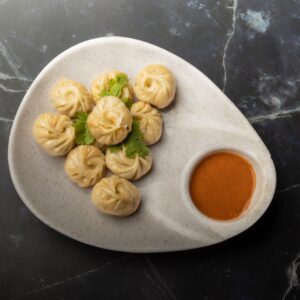 A plate of traditional Nepalese momos with spicy chutney. Perfect for food enthusiasts seeking authentic flavors.