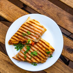 Tasty grilled paninis with parsley on a white plate, set outdoors.