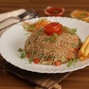 Tasty vegetable fried rice with a tomato rose and fries on a wooden background.