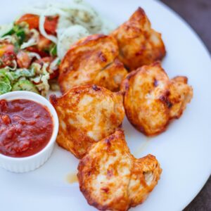 Grilled chicken served with fresh salad and salsa on a white plate.